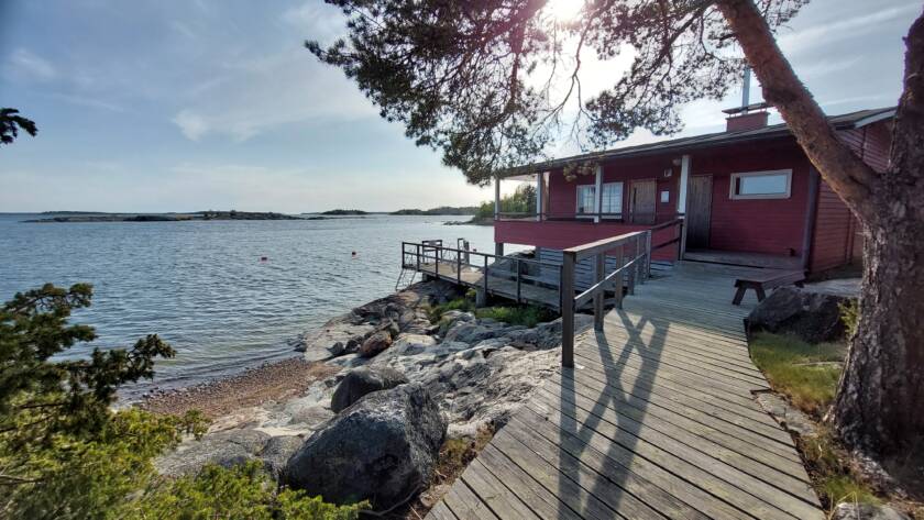 Vettä, kallioinen ranta, ja saunarakennus.