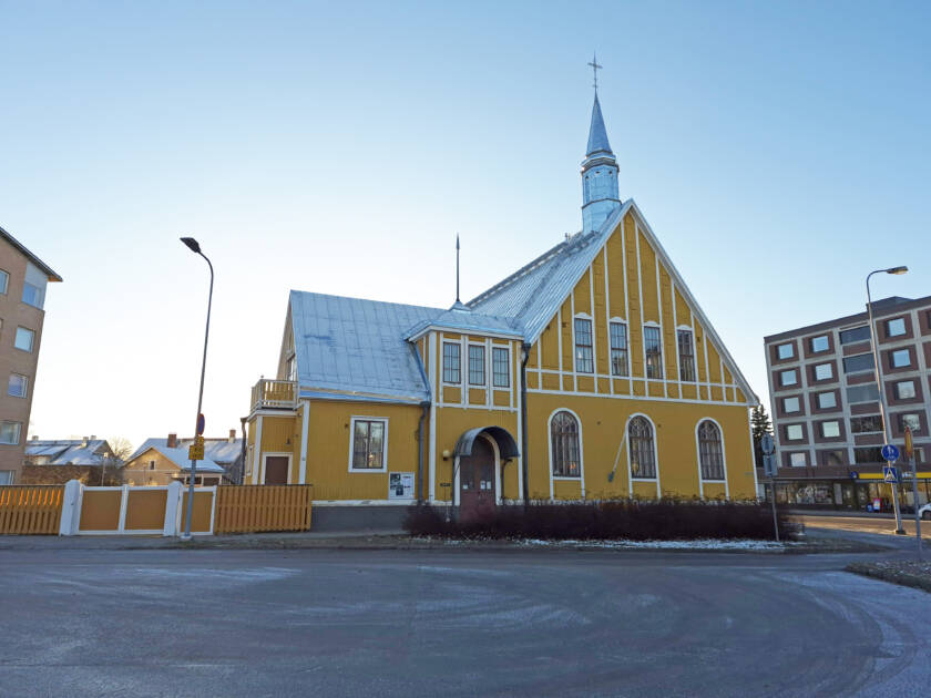 Iso keltainen rakennus, jonka edessä parkkitilaa.