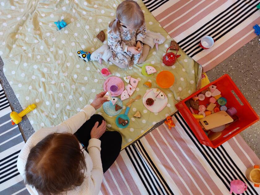 Lapsi vanhemman kanssa lelujen keskellä.