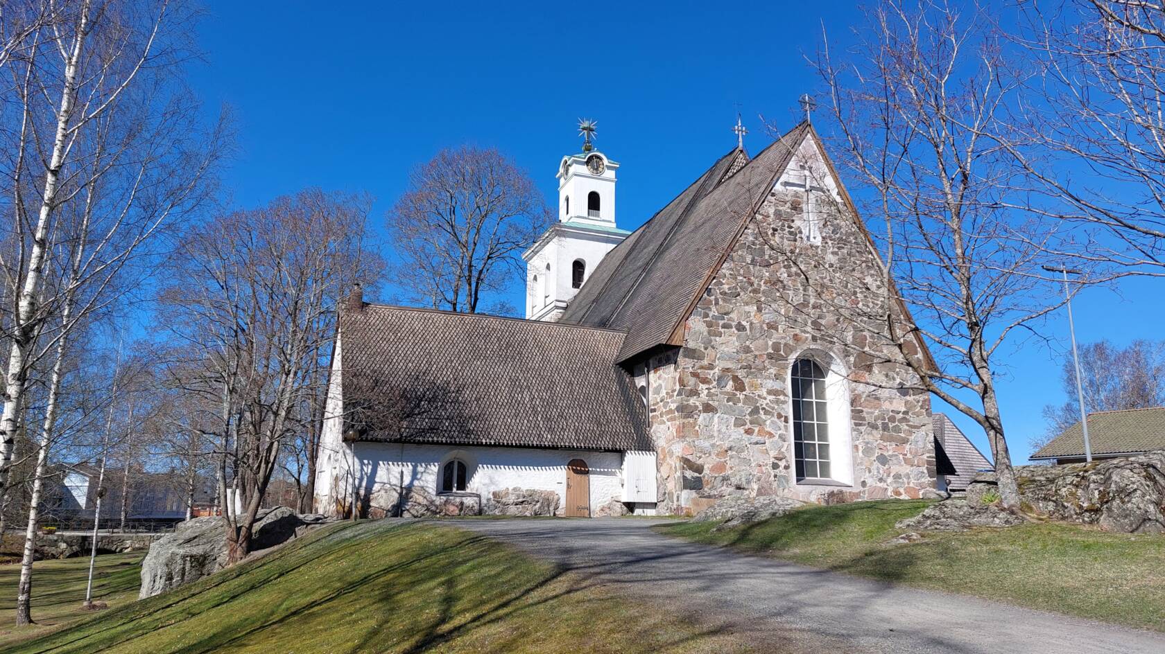 Pyhän Ristin kirkko, sininen taivas ja lehdettömiä puita.