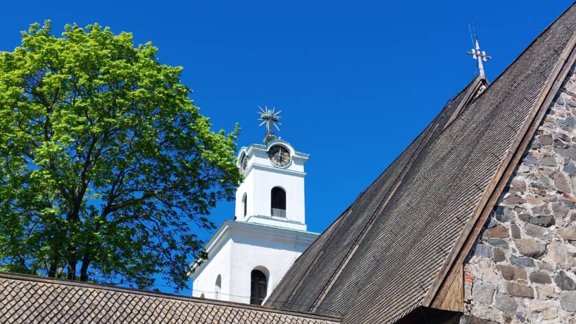 Kirkon torni ja kirkon kattoa. Kirkkaansininen taivas.