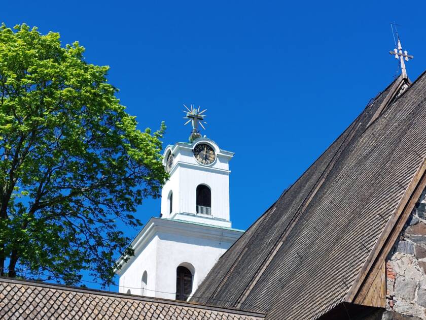 Kirkon torni ja kirkon kattoa. Kirkkaansininen taivas.