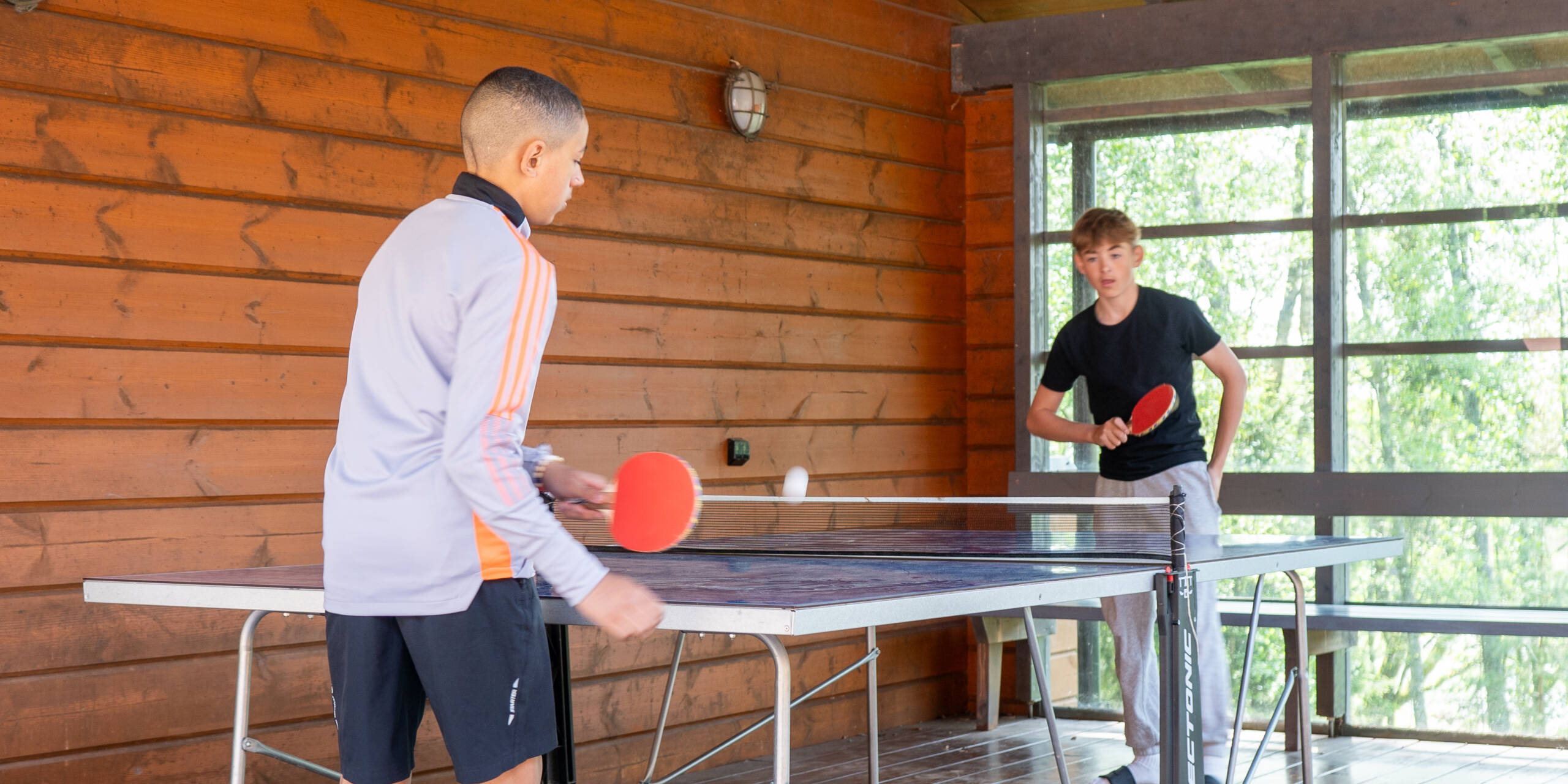 Kaksi nuorta pelaa pöytätennistä.