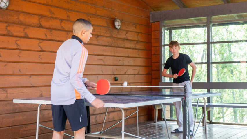 Kaksi nuorta pelaa pöytätennistä.