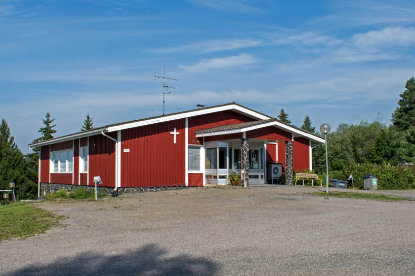 Hiekkapiha kuvan etuosassa, taaempana punainen rakennus.