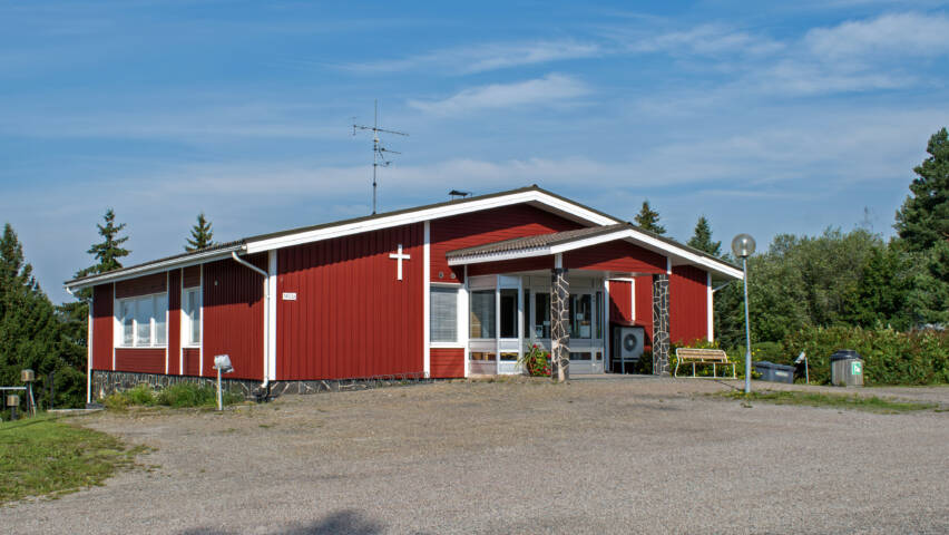 Hiekkapiha kuvan etuosassa, taaempana punainen rakennus.