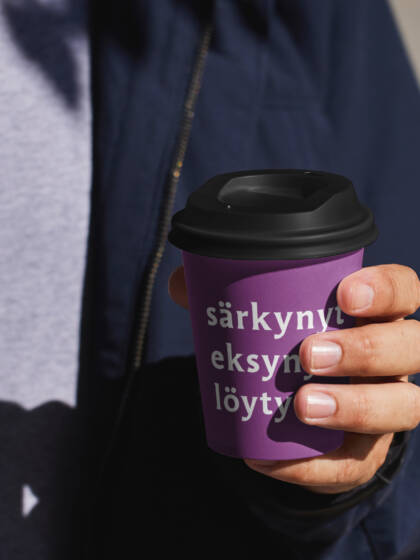 Ihminen pitää kädessään kahvimukia, jossa lukee särkynyt, eksynyt, löytynyt.