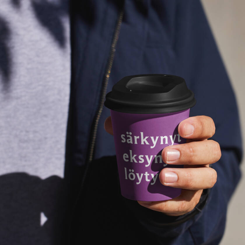 Ihminen pitää kädessään kahvimukia, jossa lukee särkynyt, eksynyt, löytynyt.