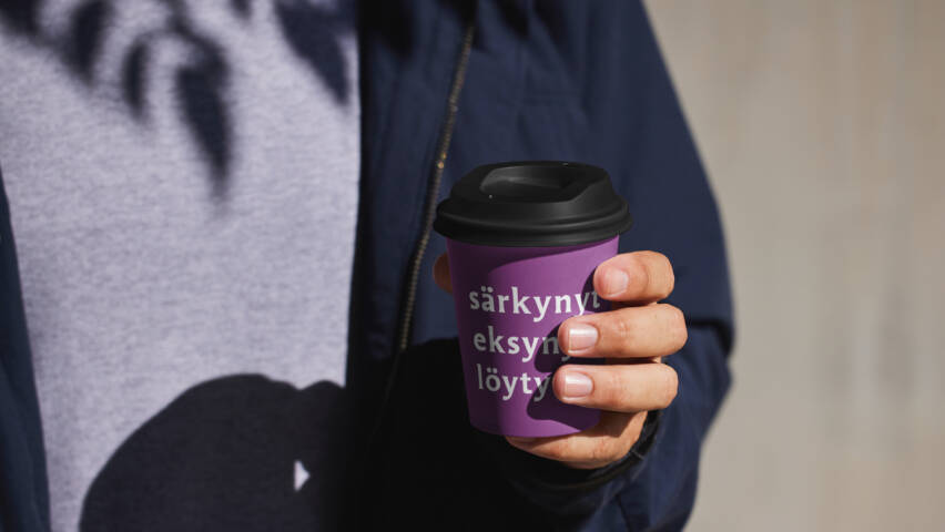 Ihminen pitää kädessään kahvimukia, jossa lukee särkynyt, eksynyt, löytynyt.