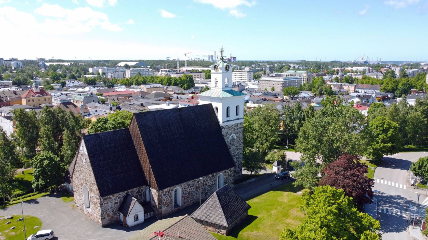 Kirkon ilmakuva, taustalla vanhaa raumaa.
