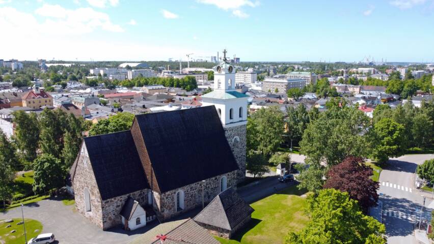 Kirkon ilmakuva, taustalla vanhaa raumaa.