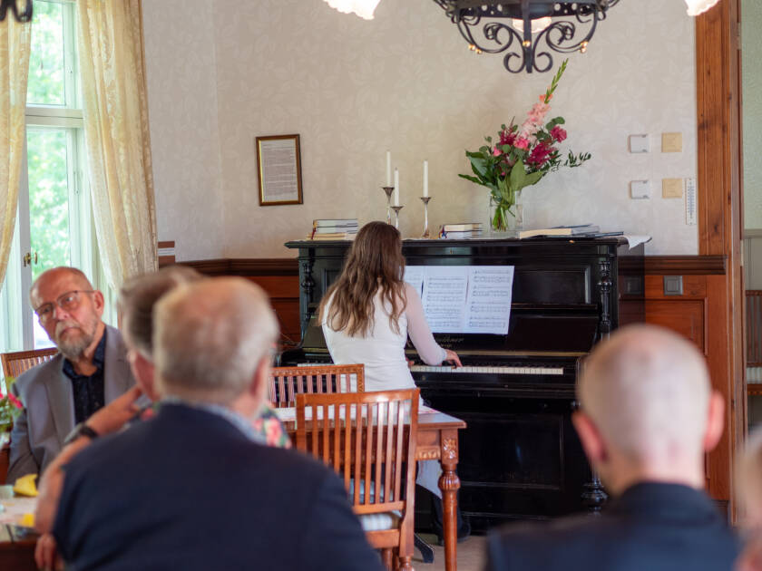Ihmisiä kuuntelemsaa pianon soittoa.